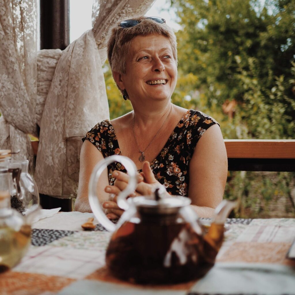Lika Megreladze sitting at a table with a teapot and glass jar.