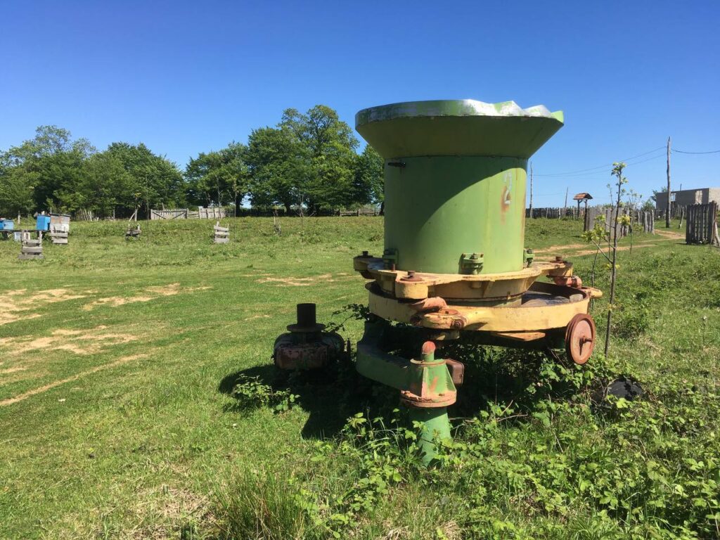 Old tea roller with a large circular top situated on a grassy area.