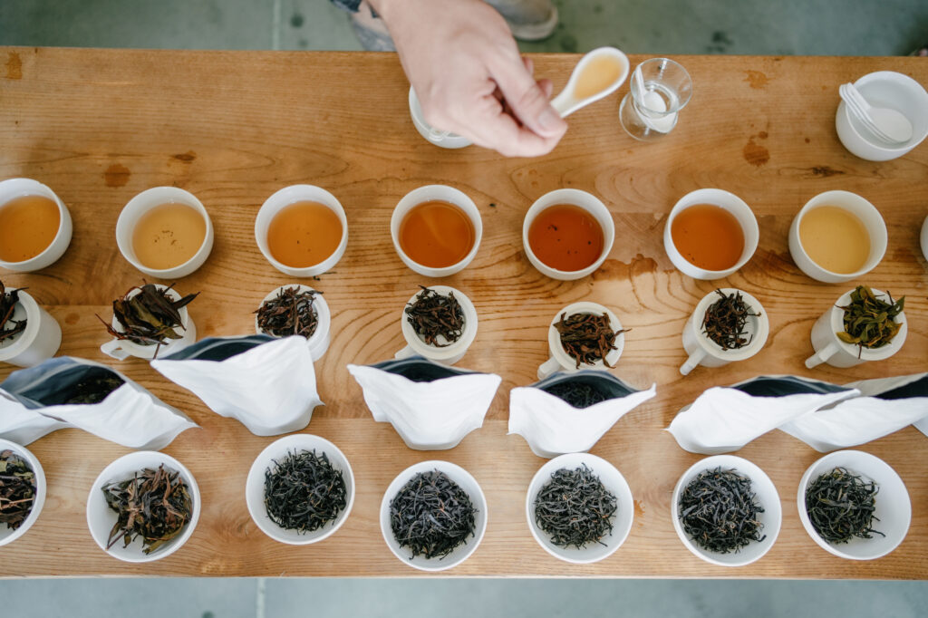 A table arranged with multiple cups of tea and tea leaves in bags for tasting at the Zemo factory